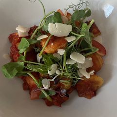 A picture of Gnocchi with mushrooms, tomato sauce and parmesan shavings.