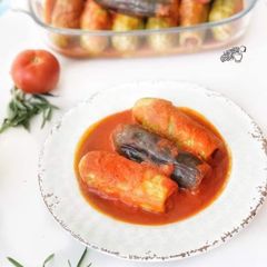 A picture of Stuffed zucchini and eggplant in tomato sauce.