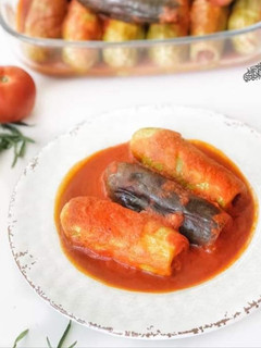 A picture of Stuffed zucchini and eggplant in tomato sauce.