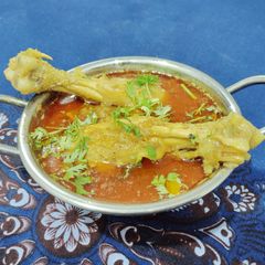 A picture of Chicken legs In red Gravy.