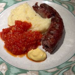 A picture of Boerewors with mashed potatoes served with a tomato chili relish.