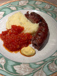 A picture of Boerewors with mashed potatoes served with a tomato chili relish.