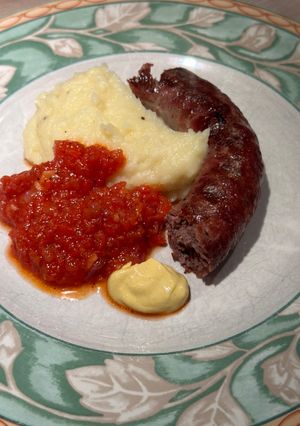 A picture of Boerewors with mashed potatoes served with a tomato chili relish.