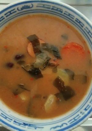 A picture of Japanese dashi miso soup with smoke sausage  twist of chilli yutaka  wakame sea weed.