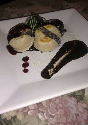 Una foto de Sorrentinos a la plancha de pollo a la mostaza con champiñones con salsa de tinta de calamar