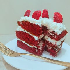 A picture of Red velvet cake with coconut frosting and strawberry toppings.