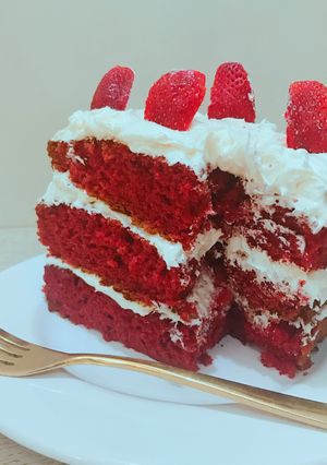 A picture of Red velvet cake with coconut frosting and strawberry toppings.