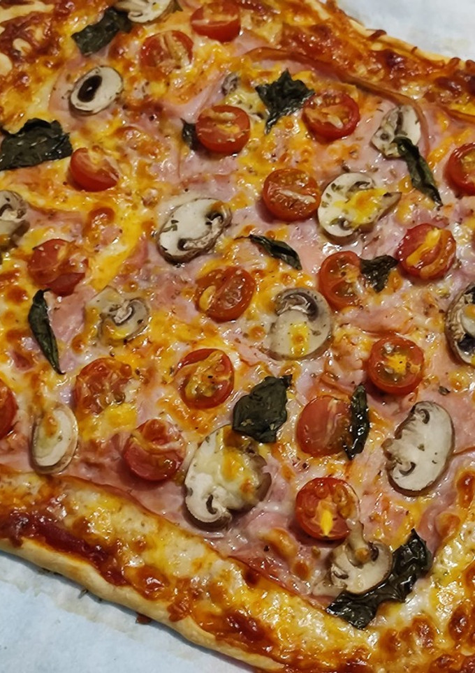 Una foto de Pizza Italiana con jamón y champiñones