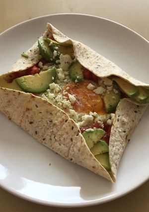 A picture of Breakfast tortilla with egg and avocado.