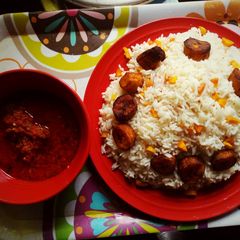 A picture of Boiled rice with tomato sauce and fried plantain.