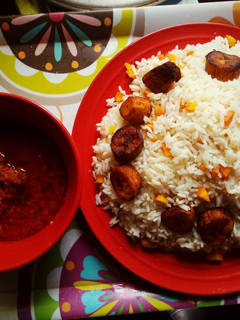 A picture of Boiled rice with tomato sauce and fried plantain.