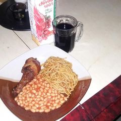 A picture of Spaghetti jollof with Baked Beans on the side.