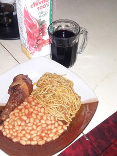 A picture of Spaghetti jollof with Baked Beans on the side.