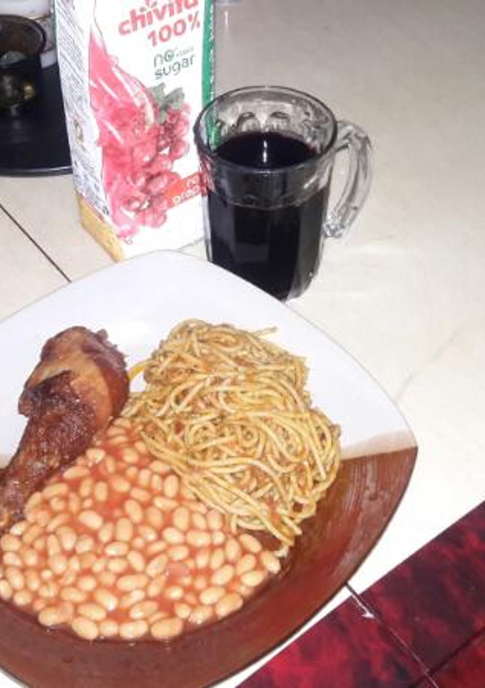 A picture of Spaghetti jollof with Baked Beans on the side.