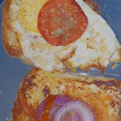 A picture of Bun-egg toast topped with sauted onions and tomatoes.