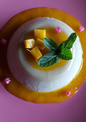 Una foto de Panna cotta de chocolate blanco con coulis de mango
