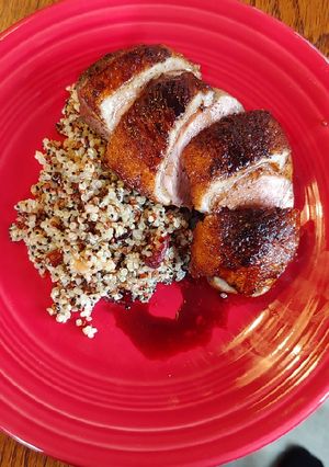 A picture of Duck Breast with cranberry walnut quinoa and balsamic reduction.