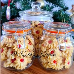 A picture of Kue Sumprit Mawar Issy (Shaped Cookies with Cherry on Top).
