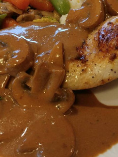 A picture of Pan Seared Chicken Breast smothered in a Crimini Mushroom Sauce.