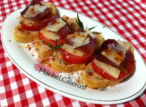 Una foto de Canapés de pan de aceitunas, tomate, queso y mojama de atún