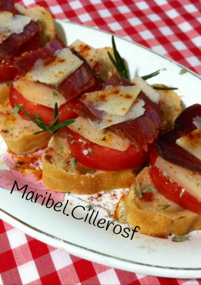 Una foto de Canapés de pan de aceitunas, tomate, queso y mojama de atún
