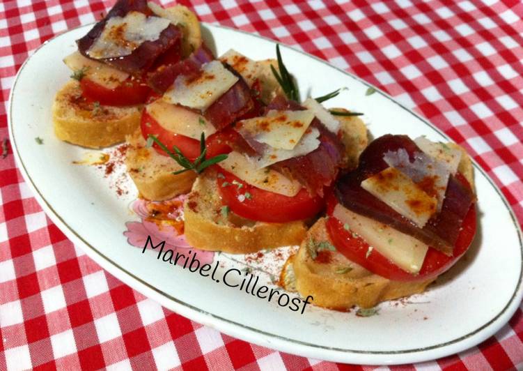 Canapés de pan de aceitunas, tomate, queso y mojama de atún
