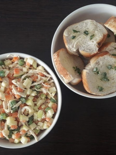 Una foto de Ensalada de pollo con tostadas de pan al ajillo.