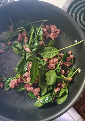A picture of Fried bacon and baby spinach.