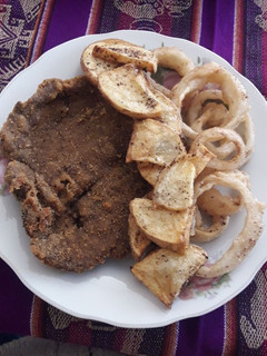 Una foto de Milanesa con aros de cebolla y papas fritas
