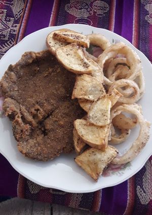 Una foto de Milanesa con aros de cebolla y papas fritas