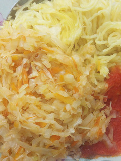 A picture of Spaghetti served with steamed cabbage and tomatoes past.