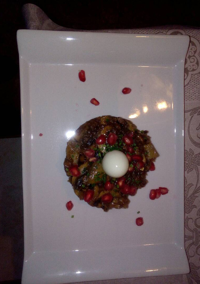Una foto de Champiñones con ajo negro y granada con huevo de codorniz