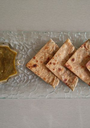 A picture of Aloo paratha with parsley chutney.