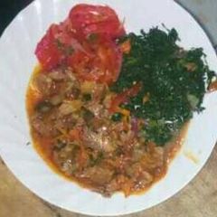 A picture of Beef stew with fried spinach and kachumbari.