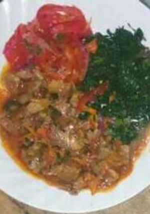 A picture of Beef stew with fried spinach and kachumbari.