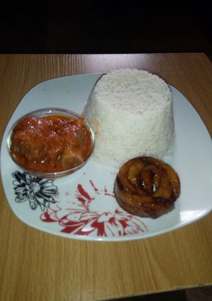 A picture of White Rice, Goat meat Stew and Fried Plantain.