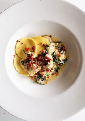 A picture of Pumpkin ravioli with a spinach sauce.
