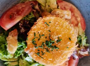 Una foto de Ensalada de lechuga de batavia y roble con queso de rulo frito