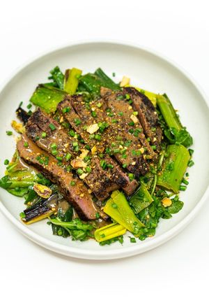 A picture of Grilled Lamb Steak with Pistachios, Charred Leeks, and Roasted Shallot Vinaigrette.