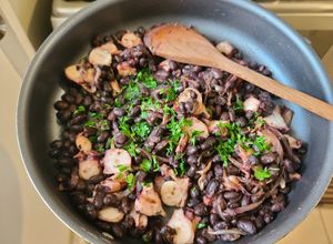 Una foto de Poroto negro con cebolla caramelizada y pulpo
