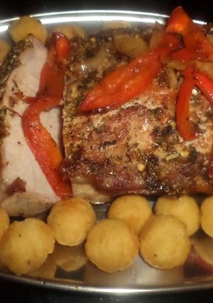 Una foto de Bondiola de cerdo en colchón de morones y cebollas caramelizadas y papas noisettes