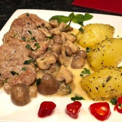 A picture of Pork muscles with mushrooms and boiled potatoes.