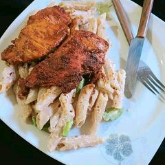 A picture of White sauce pasta with grill chicken.