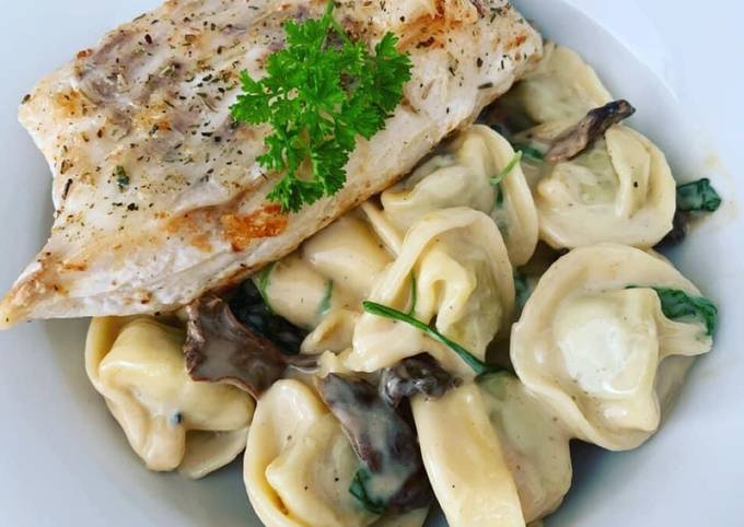 Tortellini mit einer Spinat-Waldpilz-Käsesoße dazu gebratenes Kabeljaufilet