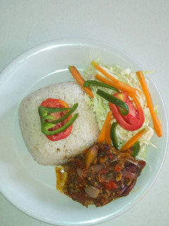 A picture of White rice with ufada stew and vegetables.