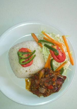 A picture of White rice with ufada stew and vegetables.