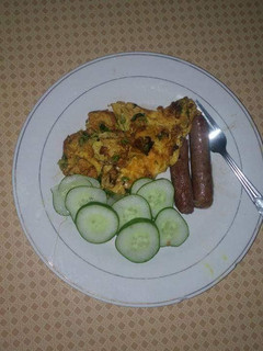 A picture of Fried sausages,eggs and cucumber.
