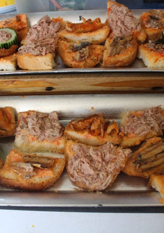 Una foto de Pan untado con tomate y latas de conserva