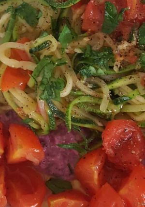 Foto di Spaghetti di zucchina sul letto di cavolo viola con fiori di ciliegino