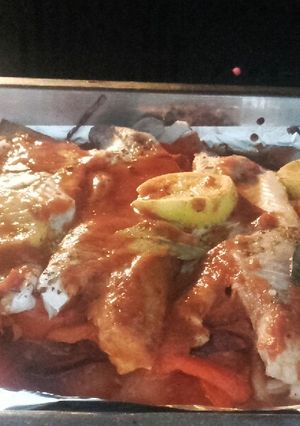 Una foto de Merluza al horno, con cebolla, morrón y tomate